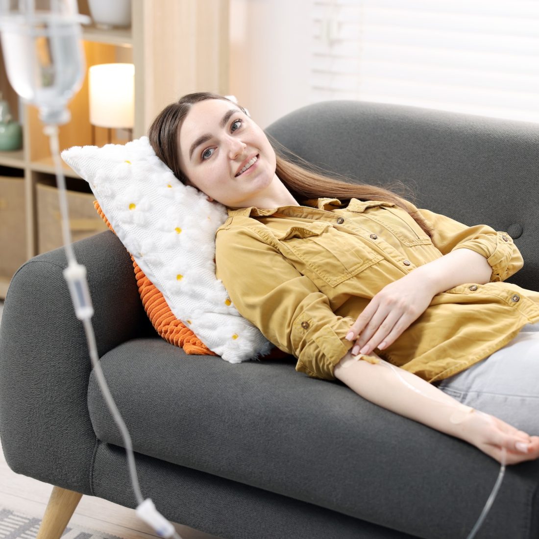 Woman with IV drip on sofa at home